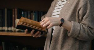 Image of a person holding a book in a library