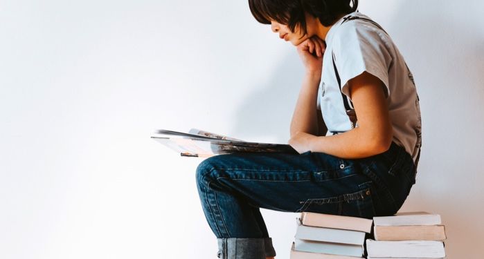 kid reading on stack of books