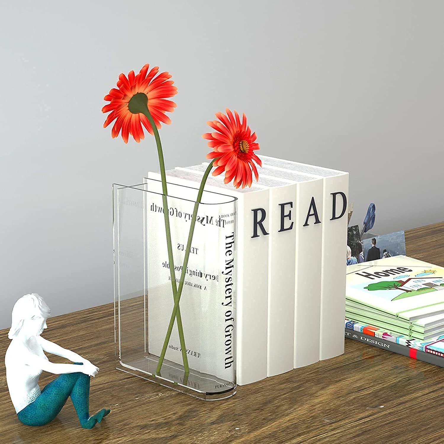 Image of a clear book vase against a stack of books.