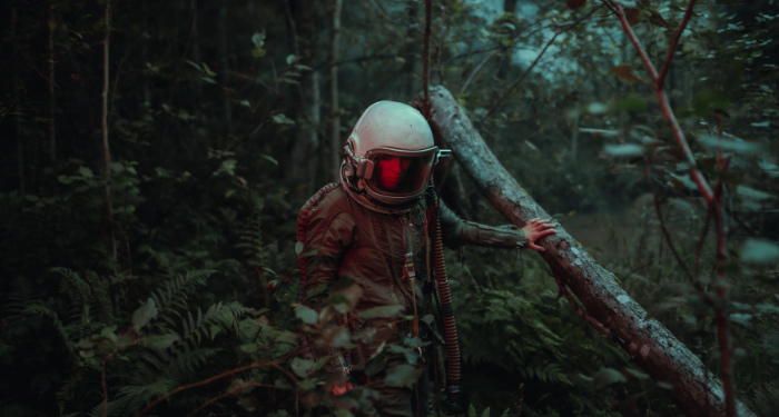 a person wearing a white helmet and a camoflage jacket walking through a forest