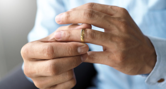 a close up photo of a man playing with the wedding ring on his finger, possibly taking it off