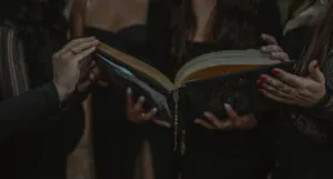 Women's hands coming together to touch a book at center