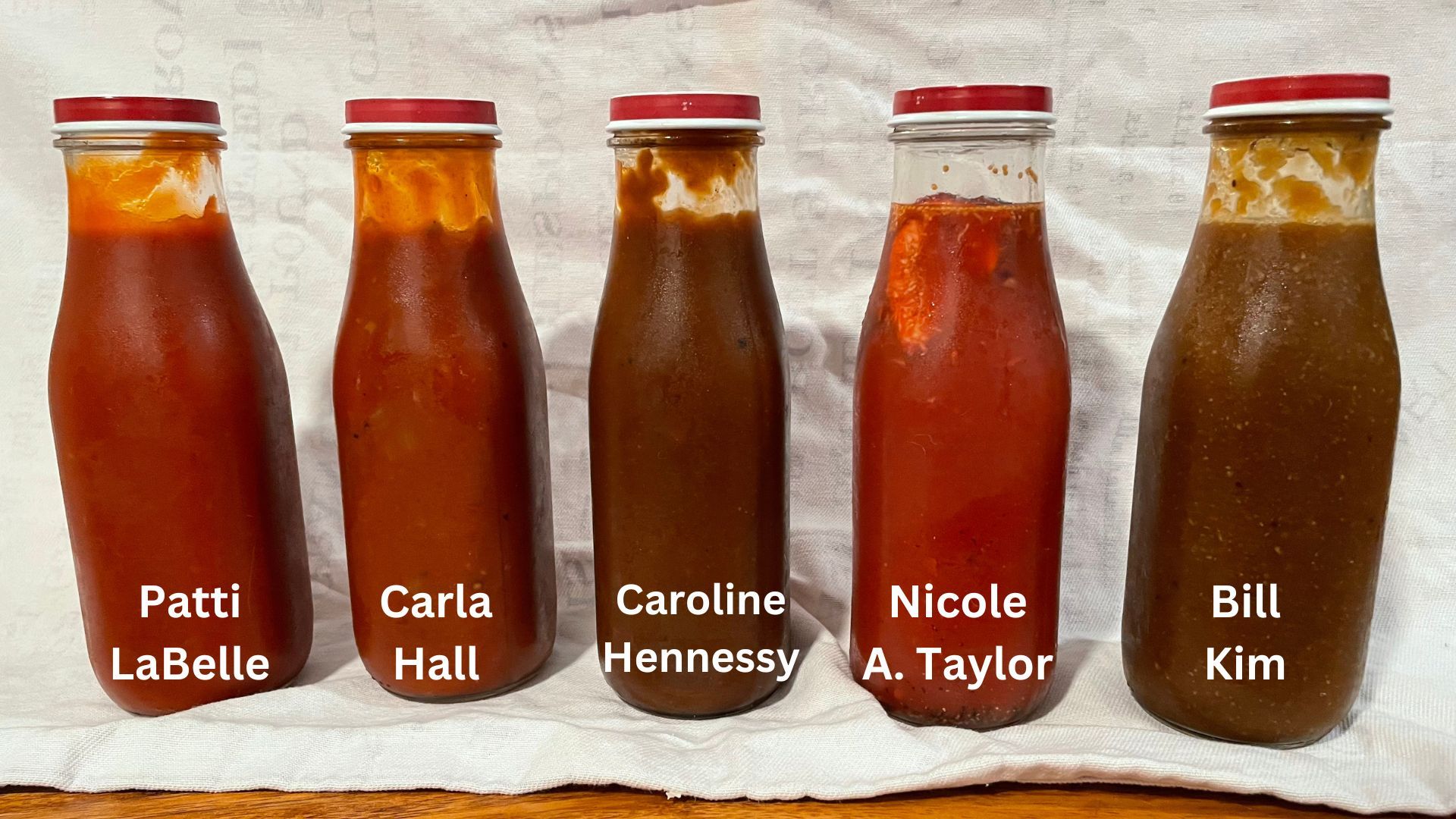 Five tall glass jars filled with BBQ sauces ranging from bright red to dark brown lined up along a white background, with the names of the cookbook authors for each edited over each bottle