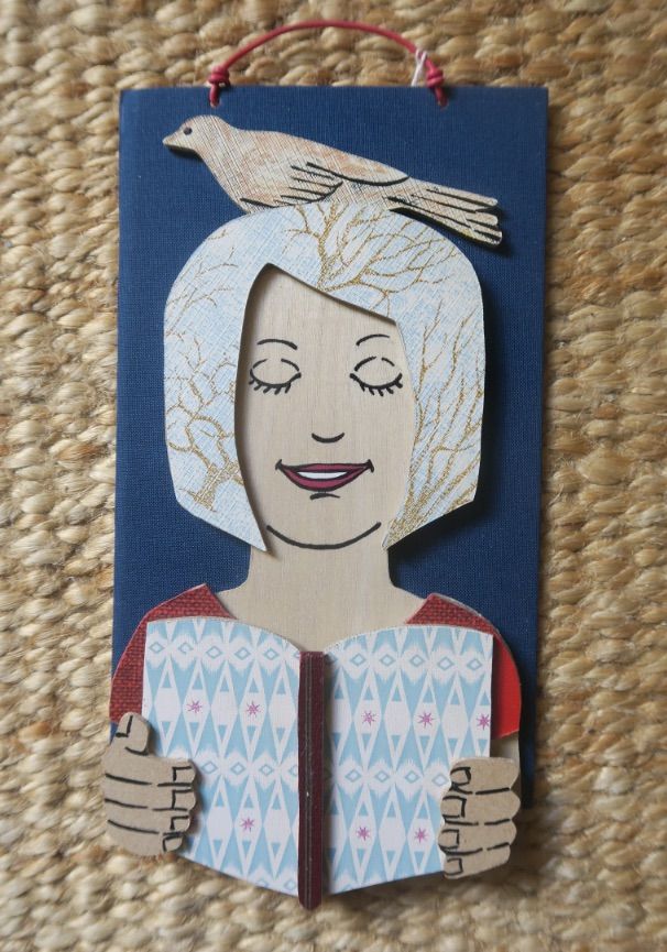 Image of a piece of art featuring a person reading with a bird on their head. 