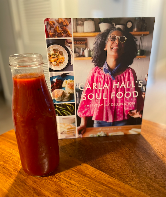 Photo of Carla Hall's Soul Food cookbook next to a tall glass jar of dark red sauce