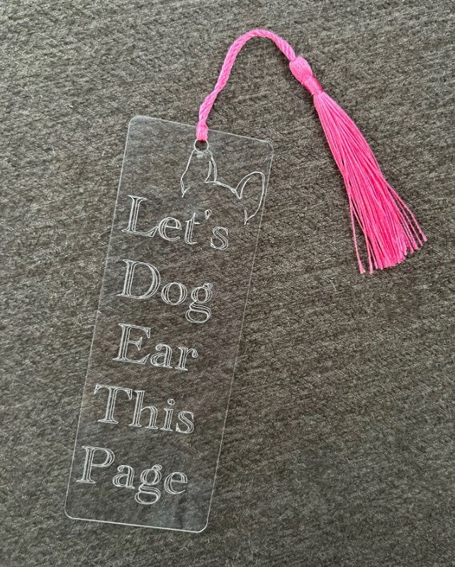 acrylic bookmark that has been engraved. It has dog ears and the words "let's dog ear this page."