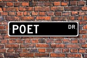 a black and white street sign that reads "Poet Dr" against a red brick background