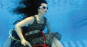 beauty is a verb cropped cover showing a person underwater sitting in a wheelchair