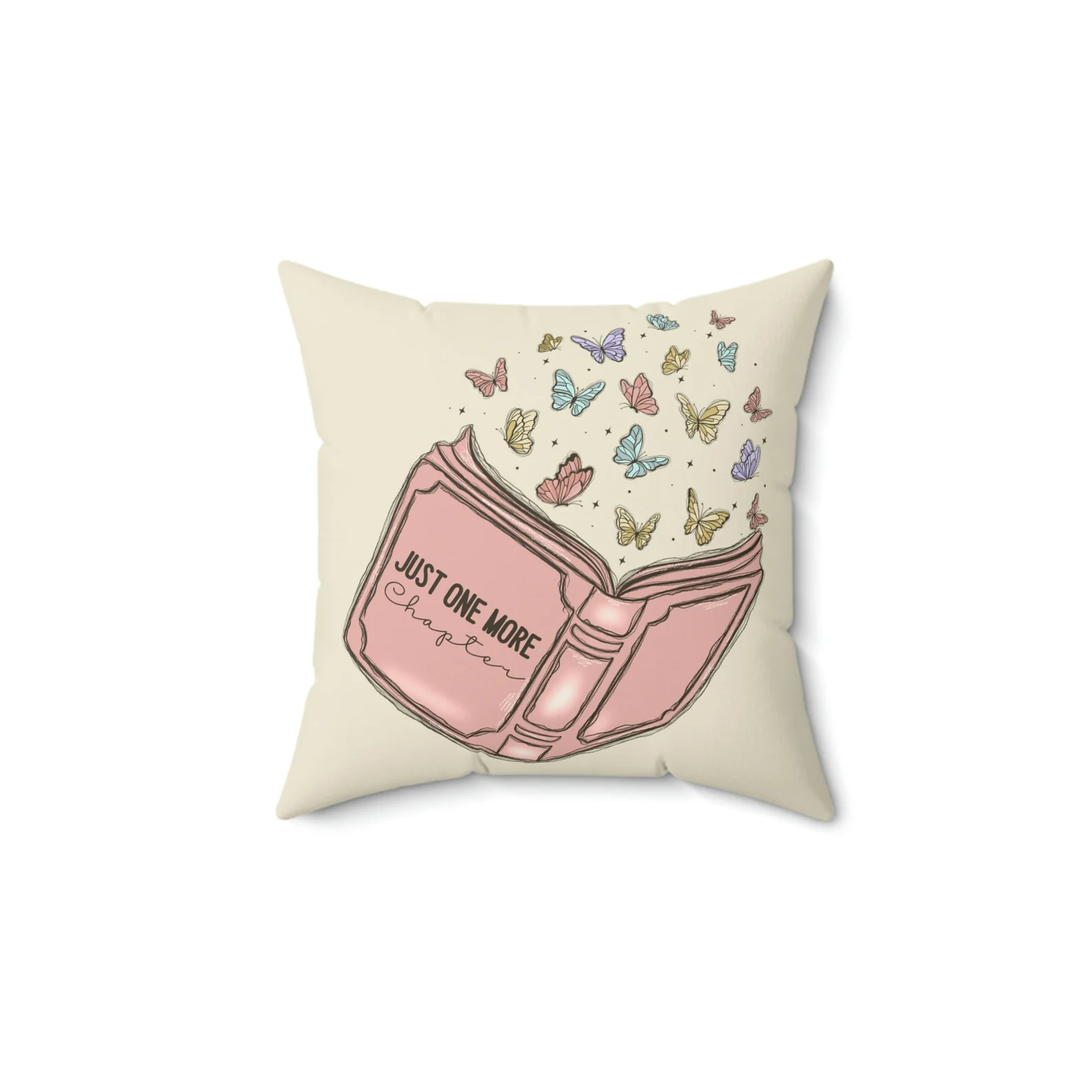 A cream pillow featuring a pink open book and butterflies that reads "Just One More Chapter"