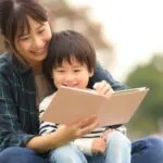 an Asian parent and child reading a picture book outside https://www.canva.com/photos/MAERRMgpWz8/