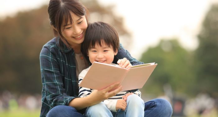 an Asian parent and child reading a picture book outside https://www.canva.com/photos/MAERRMgpWz8/
