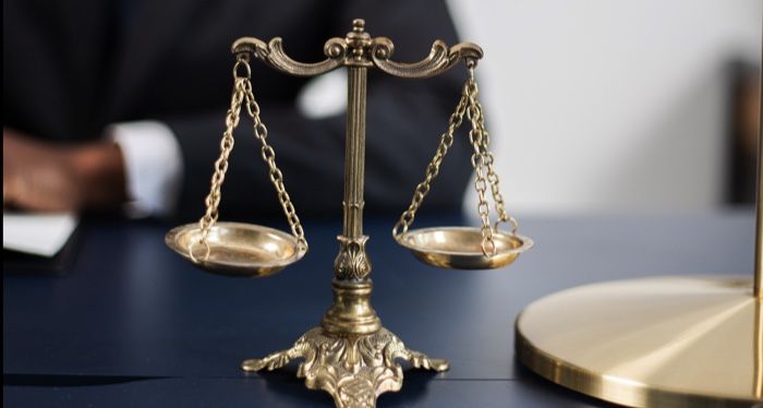 scales of justice with a brown-skinned person in the background