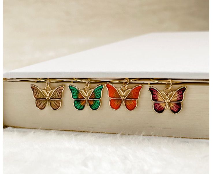 Image of four different small butterfly bookmarks on a white book.