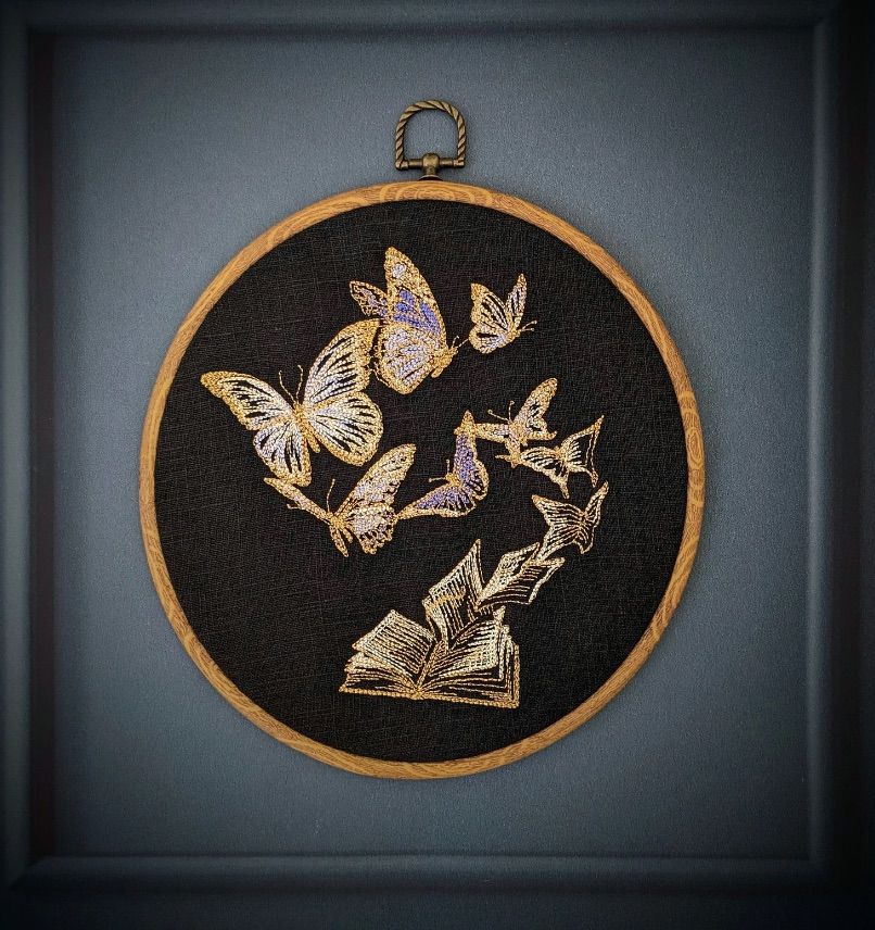Image of a work of embroidery featuring butterflies coming out of the pages of  book.