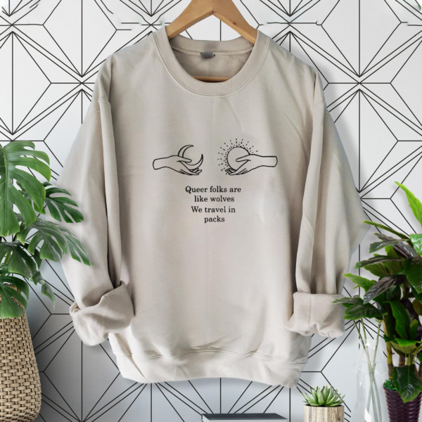 Light colored sweatshirt with printed quote from Cemetery Boys and two hands holding the sun and moon
