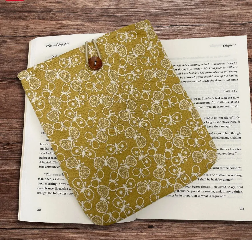 ochre colored embroidered book cover/case. The embroidery is butterflies in white thread. 