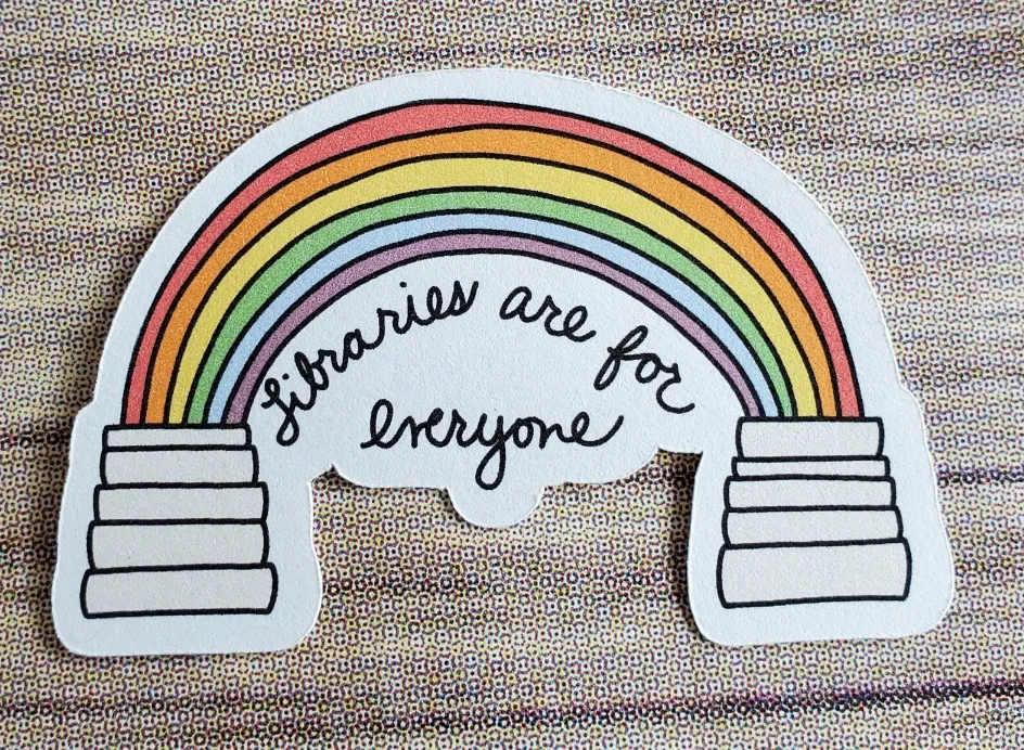 Image of a sticker with a stack of books being connected to a second stack of books with a rainbow. In black text, it reads "libraries are for everyone." 