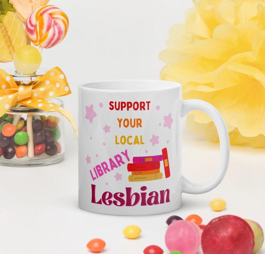 Image of a bright colored mug that reads "support your local library lesbian."