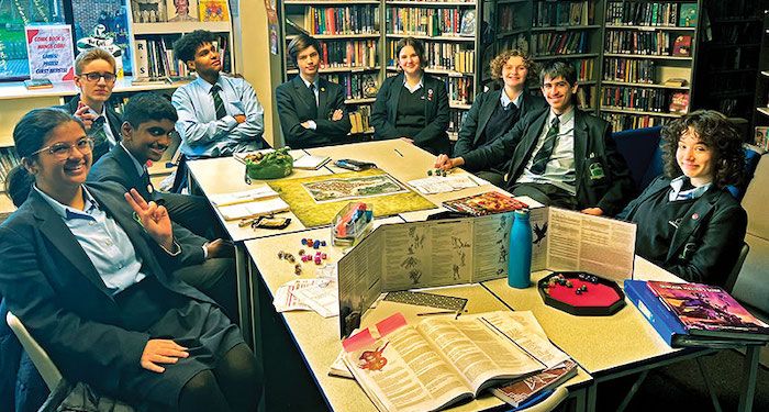 a photo of a group of teen Dungeons and Dragons players sitting around a table, smiling at the camera