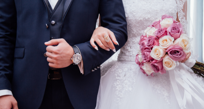 a photo of a bride and groom arm and arm, with just their torso visible