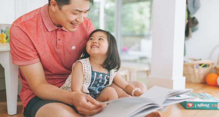 Image of an asian father and daughter reading together