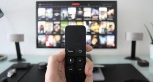 a remote being held up in front of a television displaying several streaming apps
