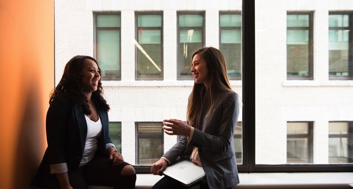 one Black woman and one white woman speaking and smiling at each other