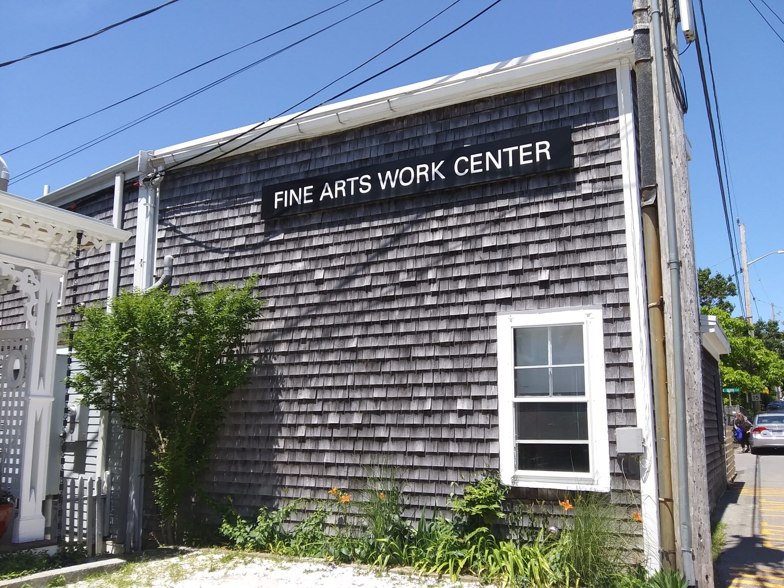 A gray-shingled building with a black-and-white sign reading Fine Arts Work Center
