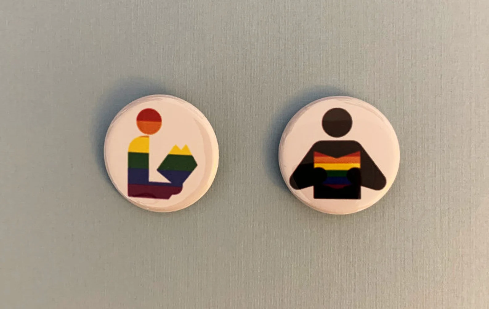 2 buttons in the shape of the library symbol. Both include books in rainbow colors. 