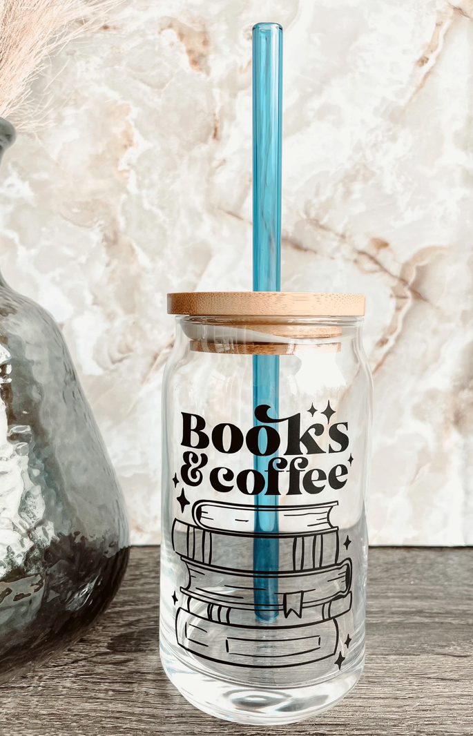 A clear glass cup that reads "books and coffee" with a bamboo lid and a blue straw