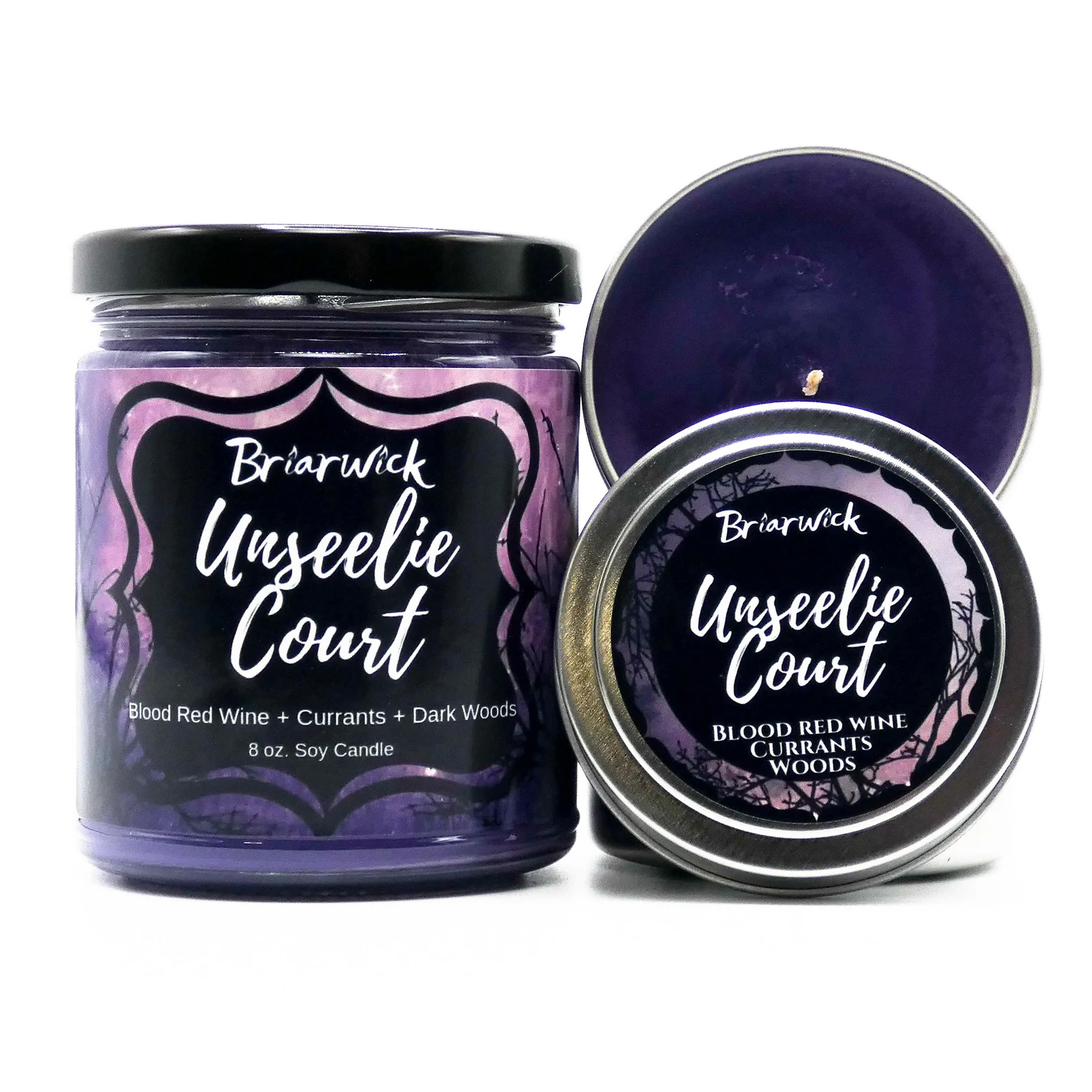 A larger purple candle in a clear glass jar sits next to a purple candle in a metal tin with the matching label Unseelie Court.