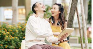 a fair-skinned Asian woman and man sitting together laughing
