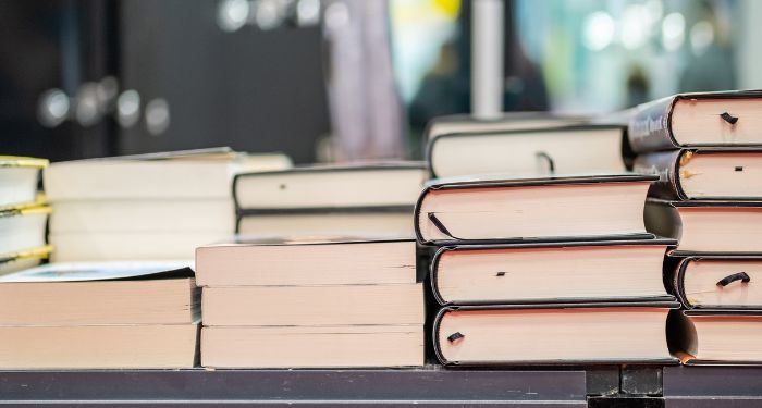 four stacks of paperback and hardcover books on a table