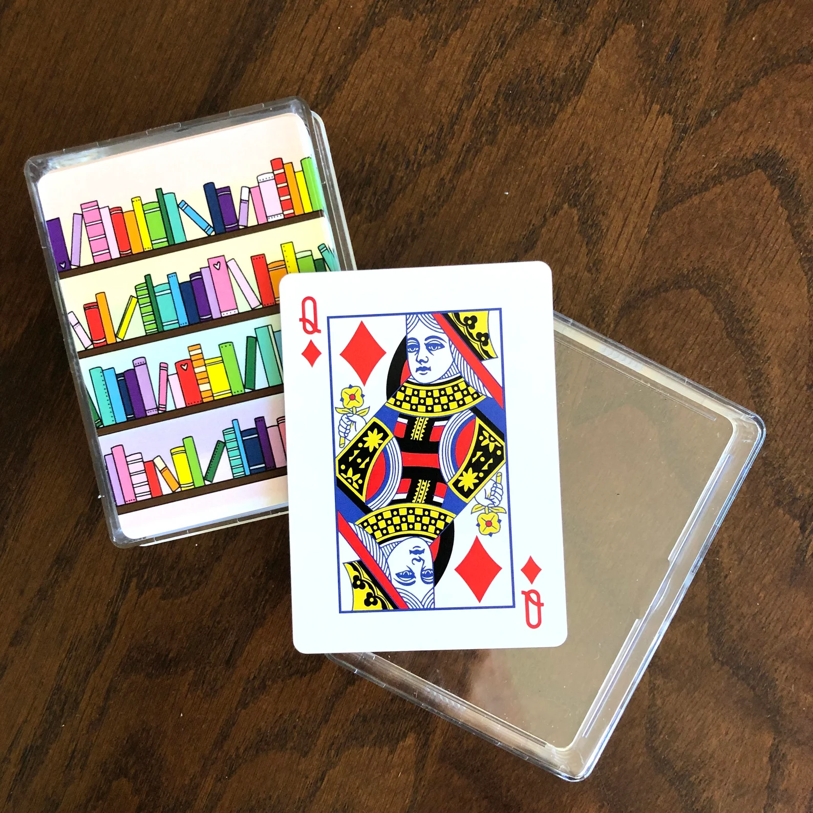 Image of playing cards where the back of the card is colorful books on shelves. 