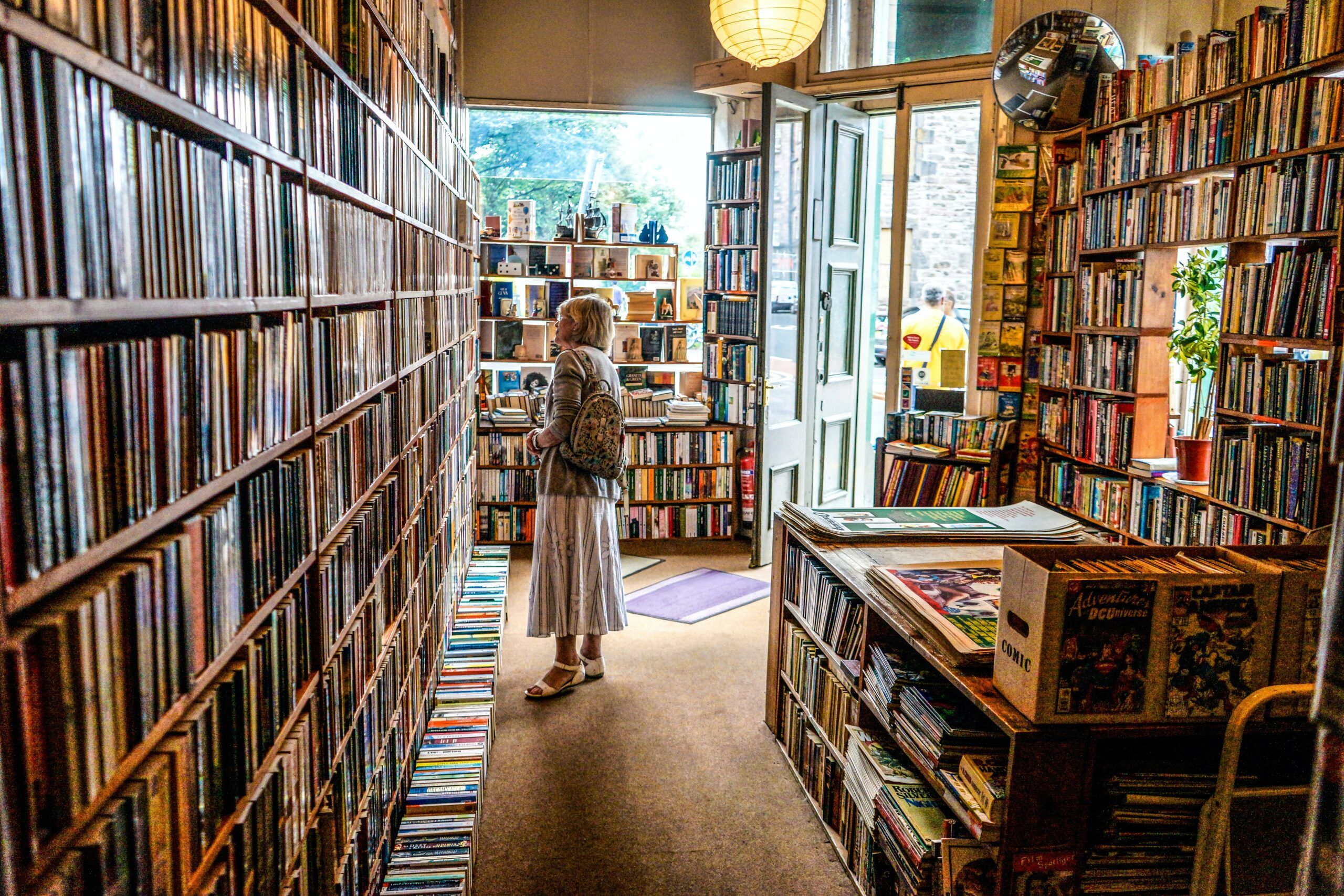 a photo of someone browsing at a bookstore with books lined up on the floor