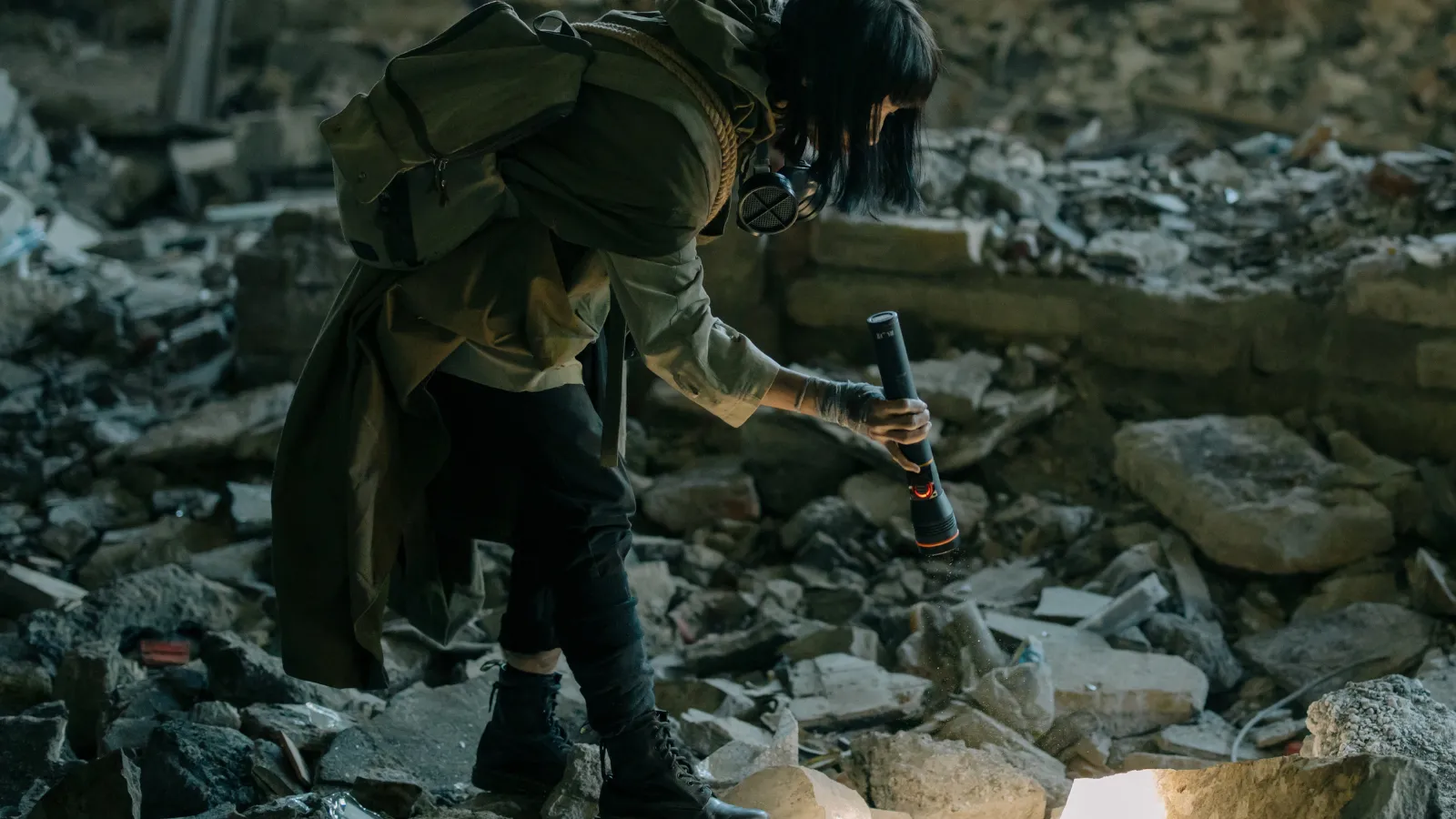 a photo of someone searching rubble with a flashlight