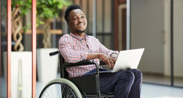 Image of a Black man using a wheel chair and lappto