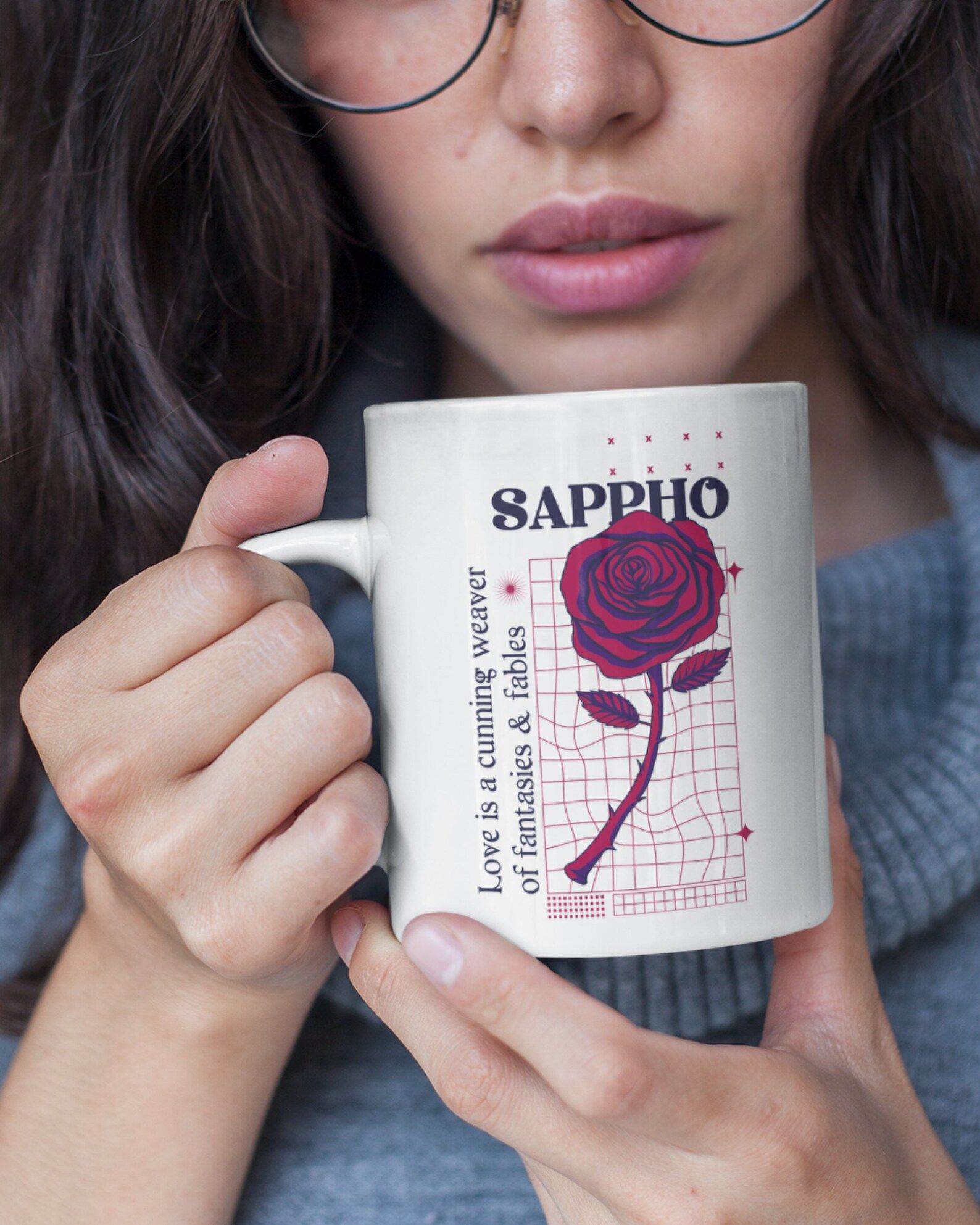 Image of a mug with a rose honoring Sappho. It is being held by a person with olive skin. 