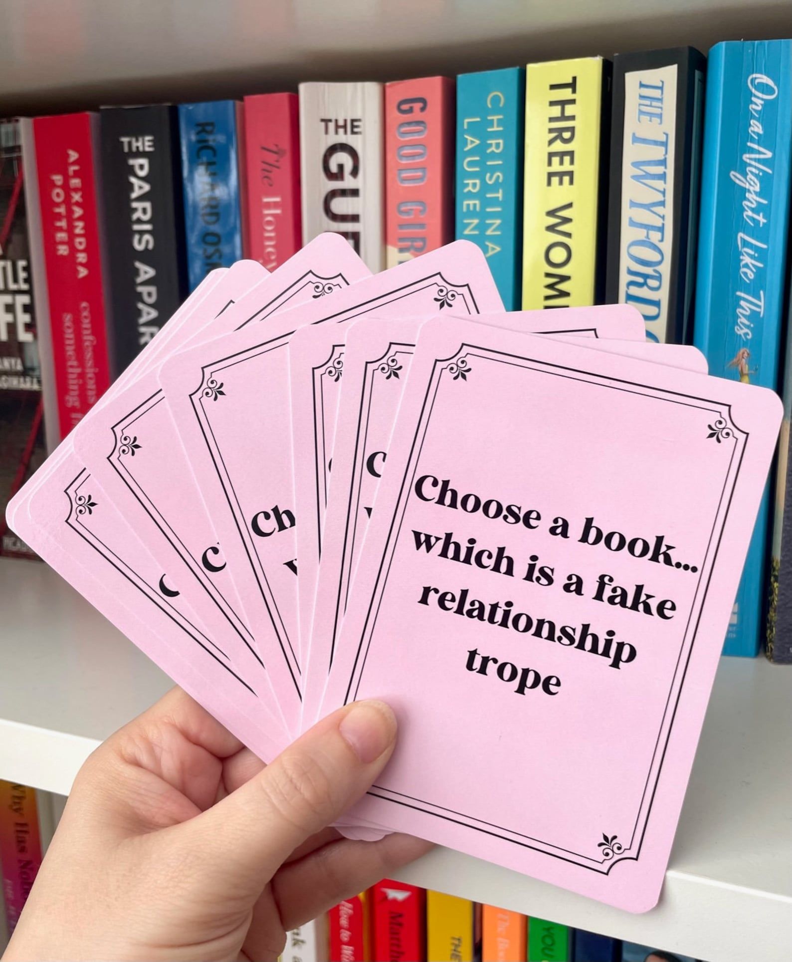 set of pink cards with black writing that prompts various books, such as 