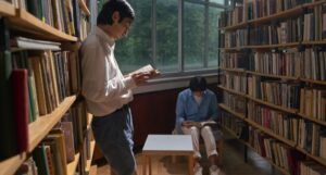 two lighter-skinned men of color readig in a library