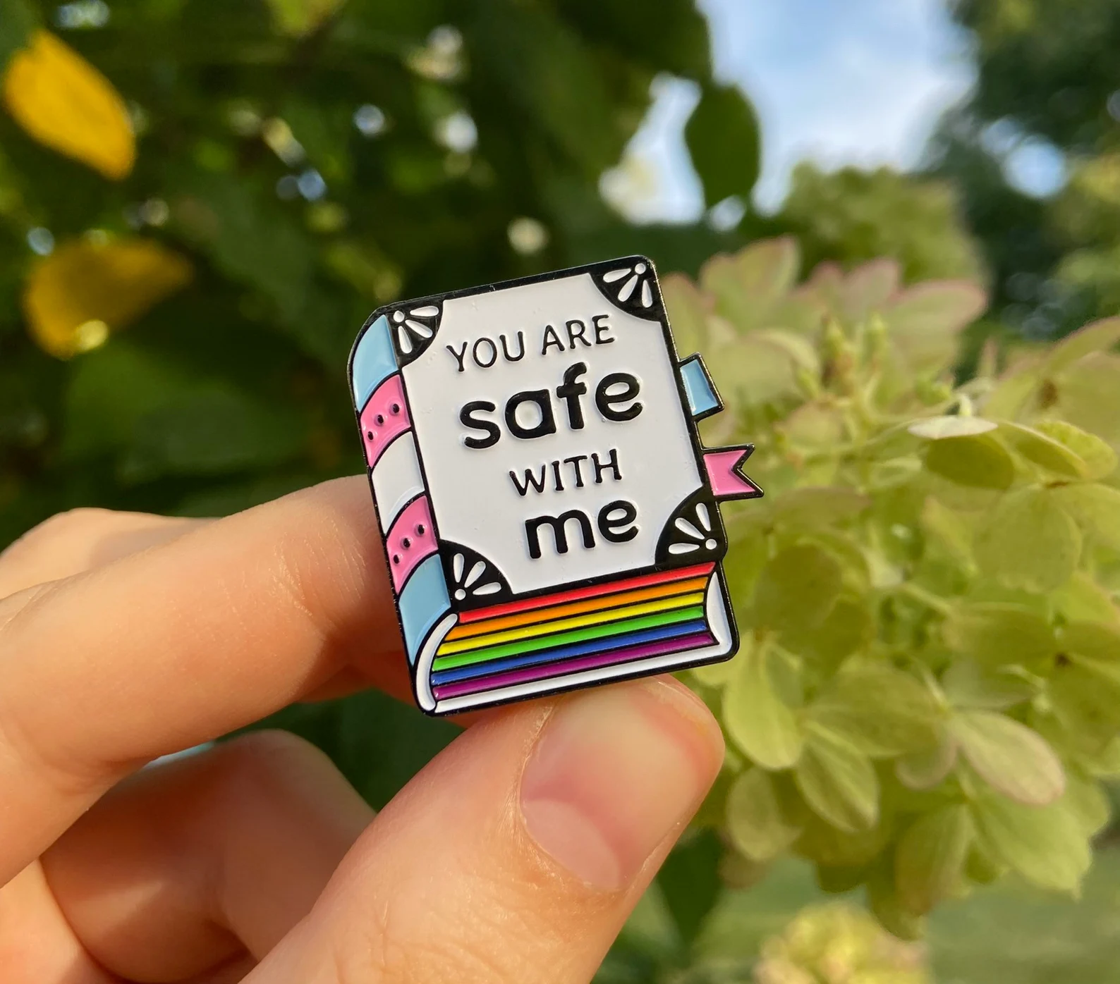 pin in the shape of a book that says "you are safe with me"