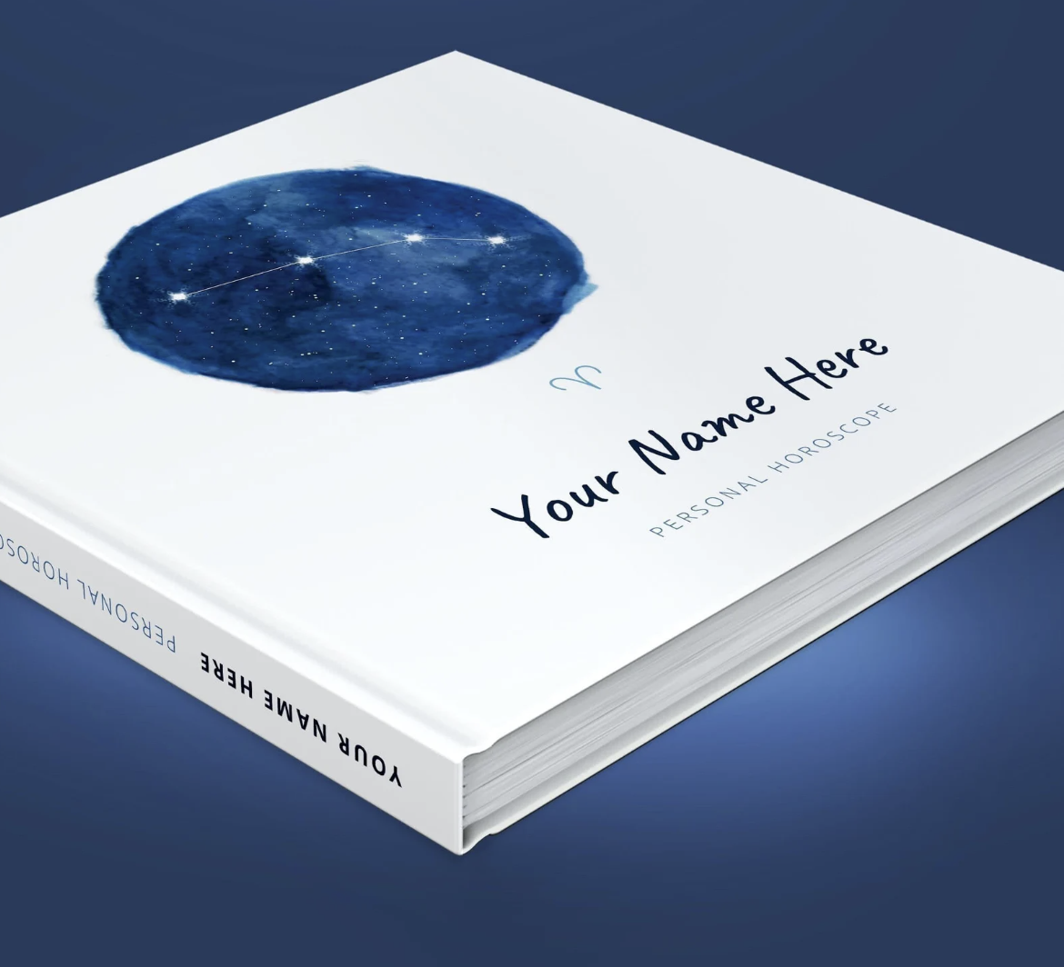 A white hardcover book with a blue circle and constellation that says "Your Name Here" resting on a blue background