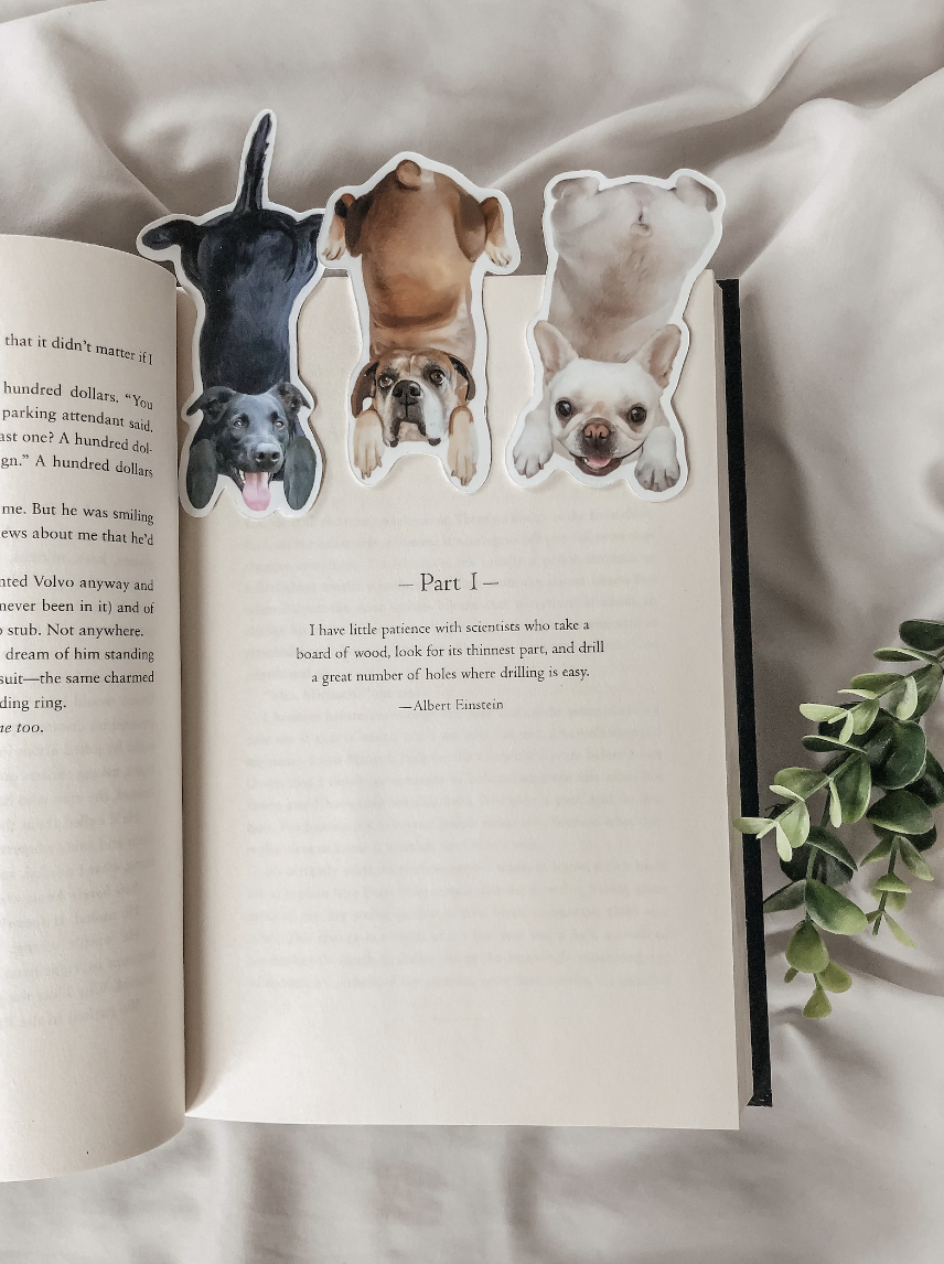 An open book with three bookmarks made from full-body photos of dogs 