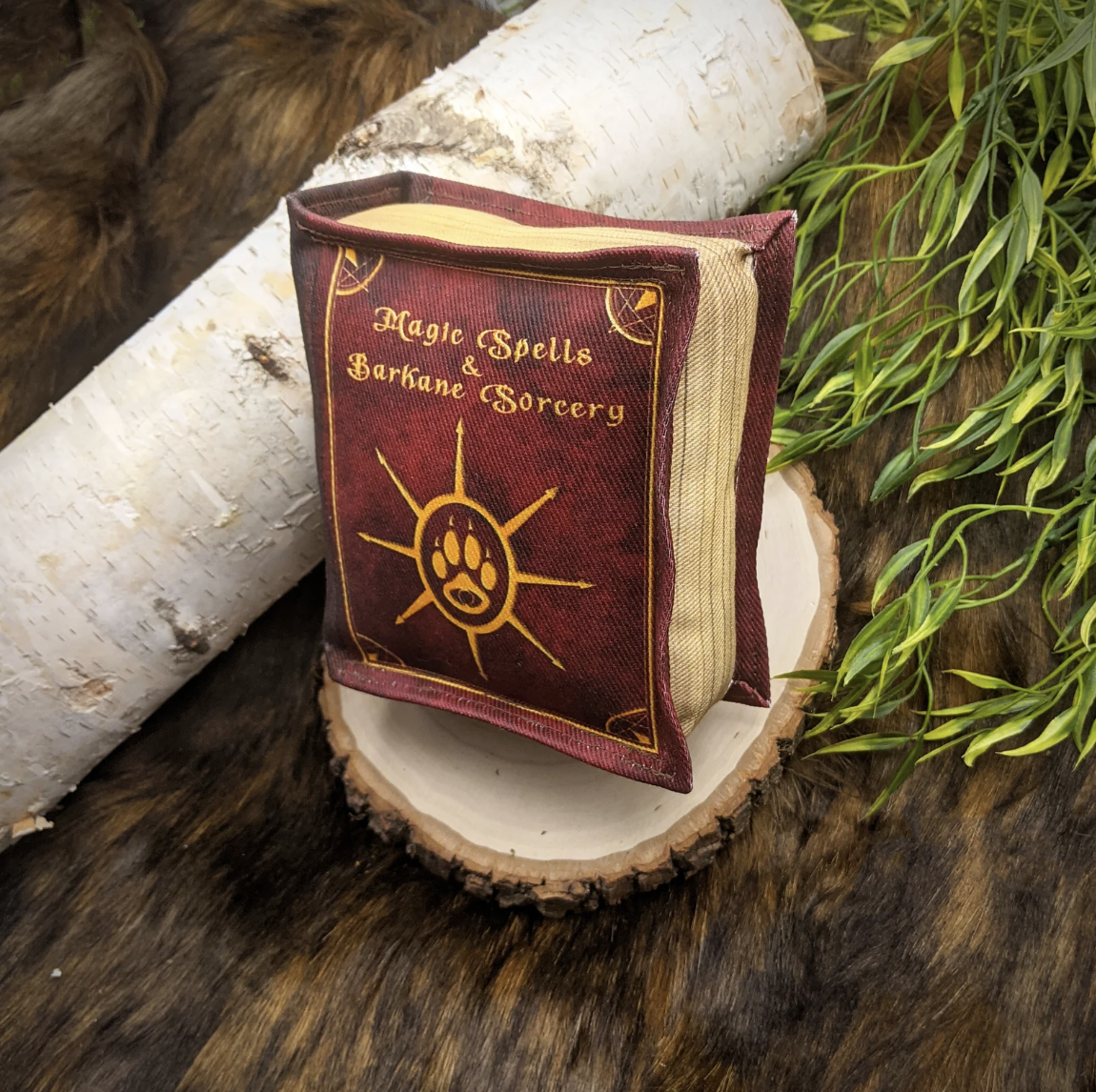 A stuffed dog toy in the shape of a book with a title "Magic Spells and Barkane Sorcery"