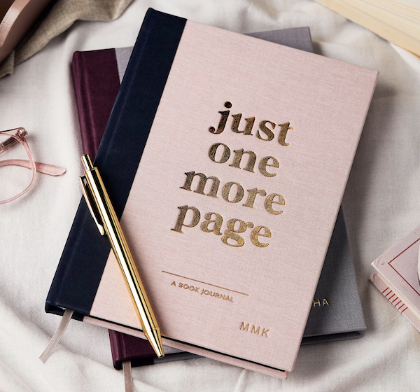 light pink book journal that says "just one more page" in gold letters on cover