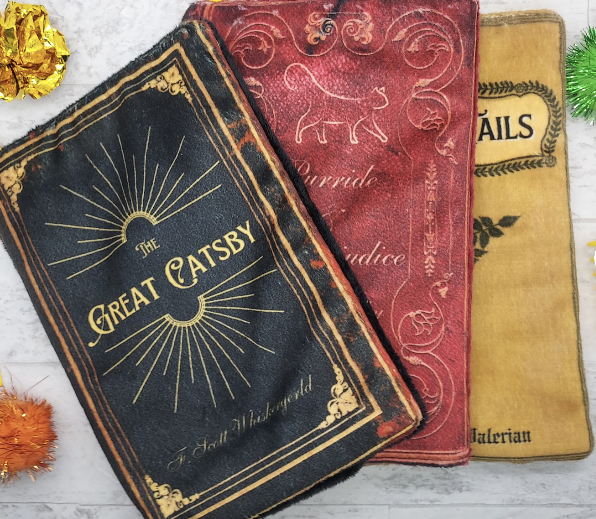 three fabric fake books that can be stuffed with catnip; the first says "The Great Catsby"