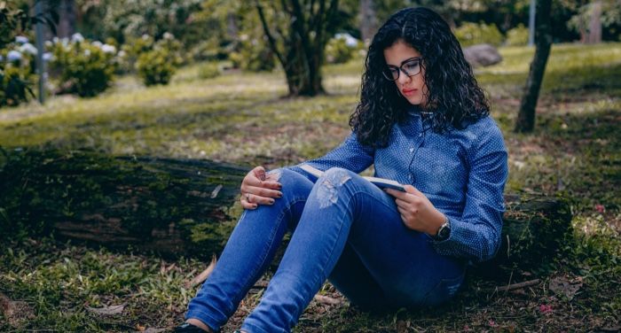 a fair-skinned Latine woman reading in the grass