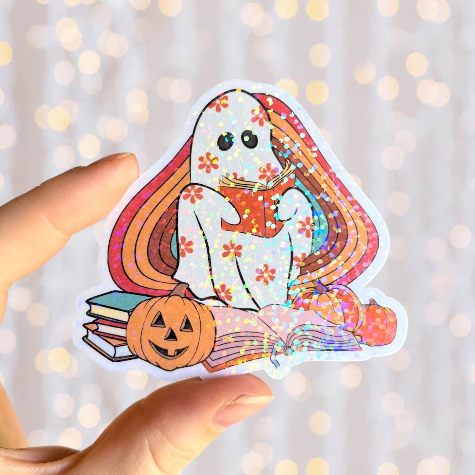 sticker of a book reading ghost in front of an autumnal rainbow