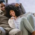 a Black couple relaxing and smiling on a couch together