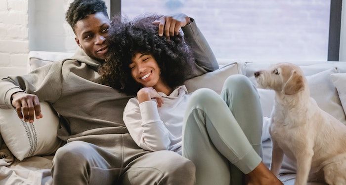 a photo of a Black couple relaxing and smiling on a couch together